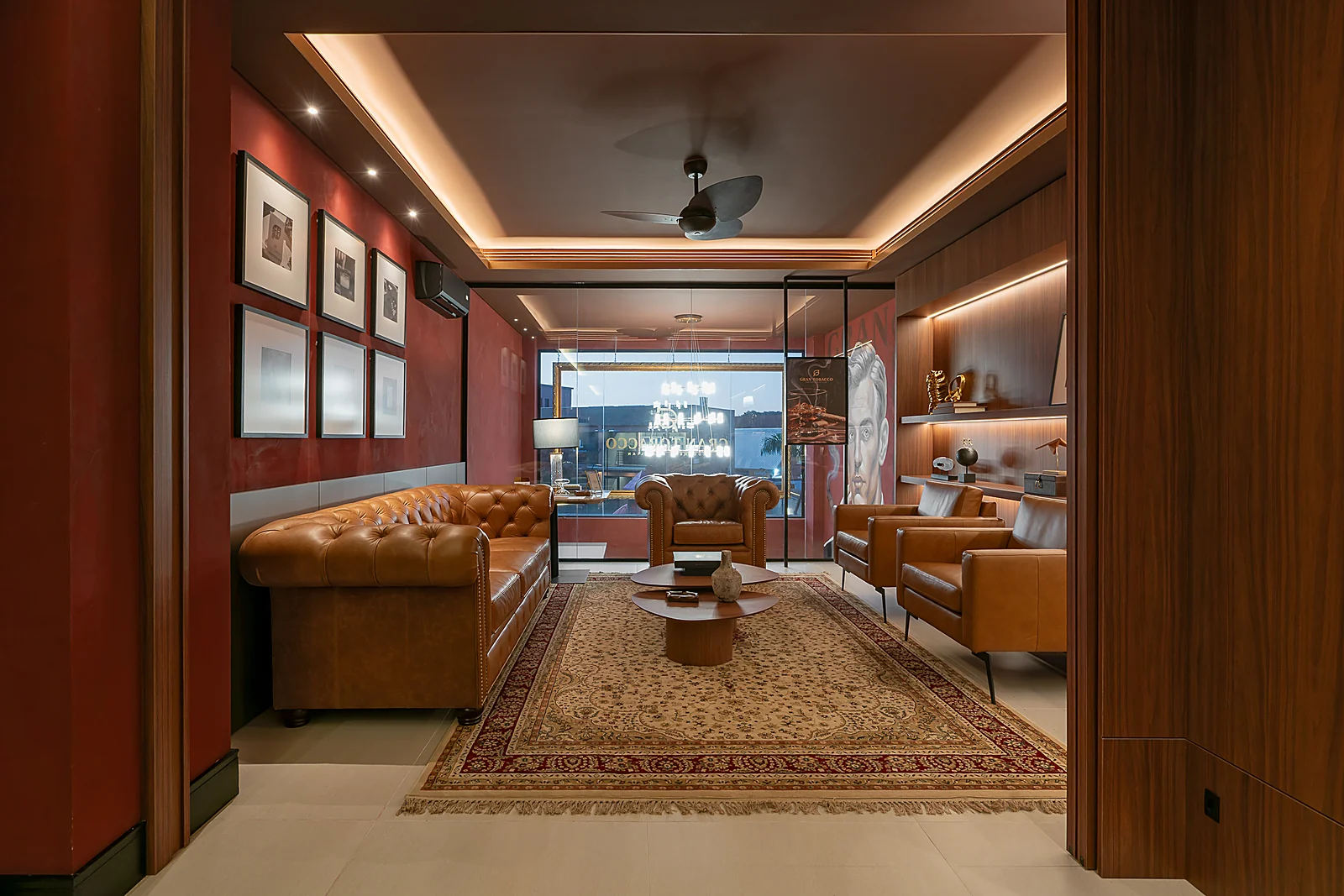 Mezanino do Gran Tobacco com sofás Chesterfield de couro, parede em tom terracota e obras emolduradas