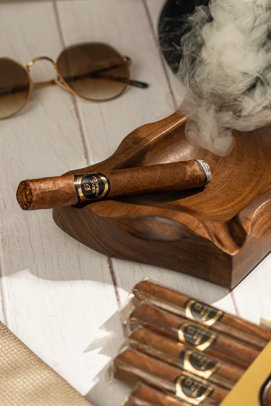 Charuto Gran Tobacco Específico aceso sobre cinzeiro de madeira, com fumaça