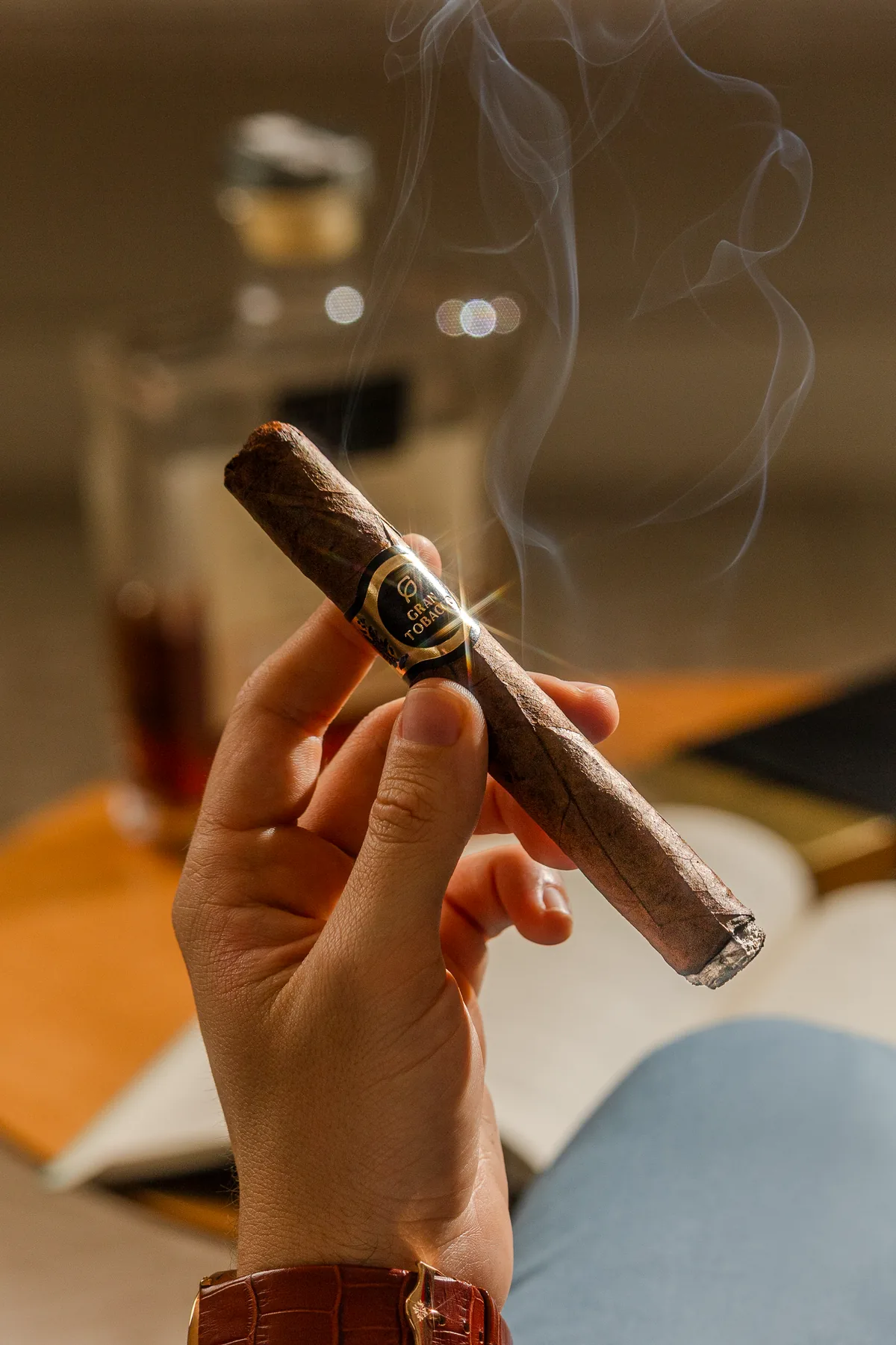 Charuto Gran Tobacco aceso entre os dedos, com fumaça sutil